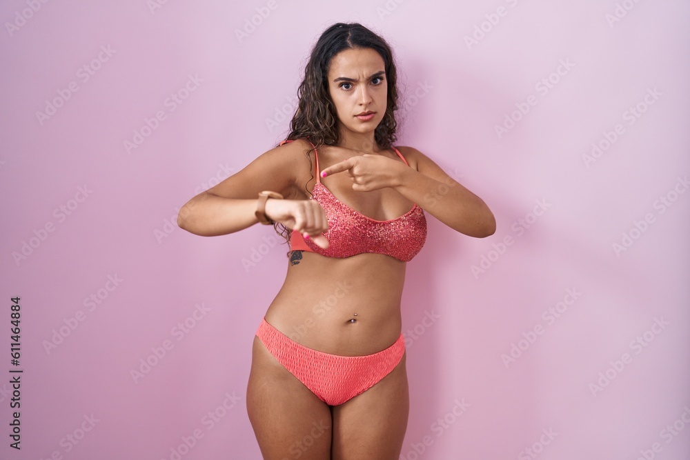 Young hispanic woman wearing lingerie over pink background in hurry pointing to watch time, impatience, upset and angry for deadline delay Young hispanic woman wearing lingerie over pink background in hurry pointing to watch time, impatience, upset and angry for deadline delay