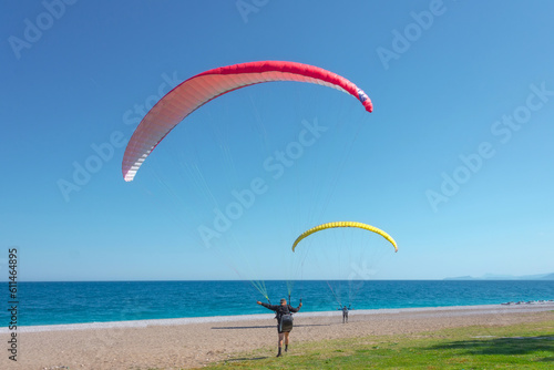 Two people paraglider are preparing to take off on a light breeze wind on the coast of the sea.