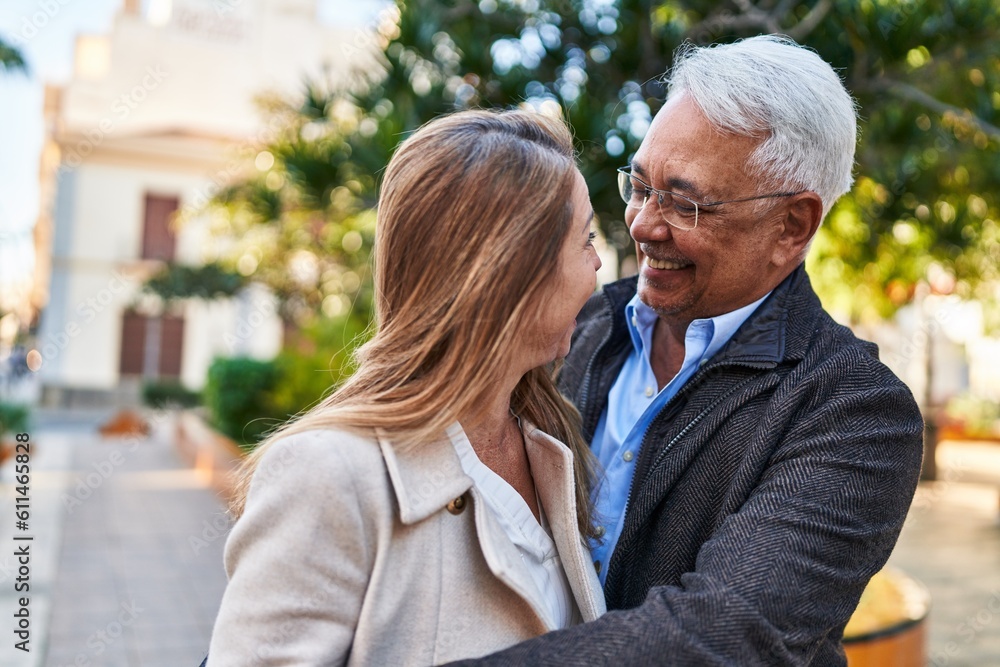 Middle age man and woman couple hugging each other standing at park
