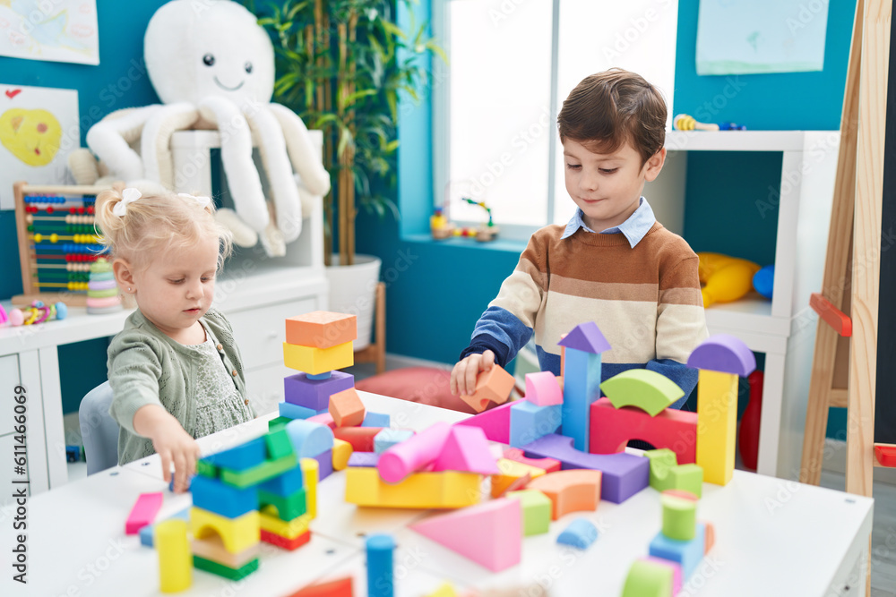 Adorable boy and girl playing with construction blocks sitting on table at kindergarten Adorable boy and girl playing with construction blocks sitting on table at kindergarten