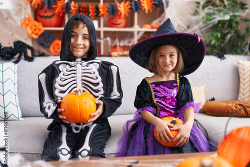 Adorable boy and girl having halloween party holding pumpkin at home