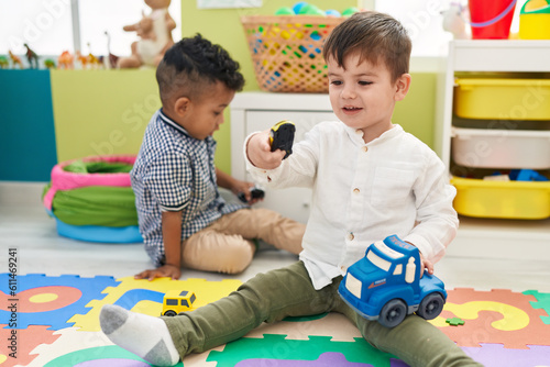 Adorable boys playing with cars toy sitting on floor at kindergarten