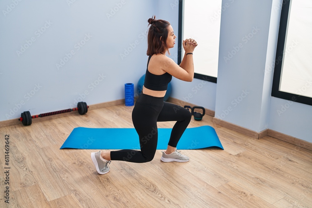 Young beautiful hispanic woman training legs exercise at sport center Young beautiful hispanic woman training legs exercise at sport center