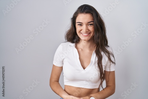 Young teenager girl standing over white background with hands together and crossed fingers smiling relaxed and cheerful. success and optimistic