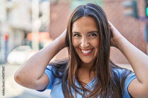 Young beautiful hispanic woman smiling confident relaxed with hands on head at street