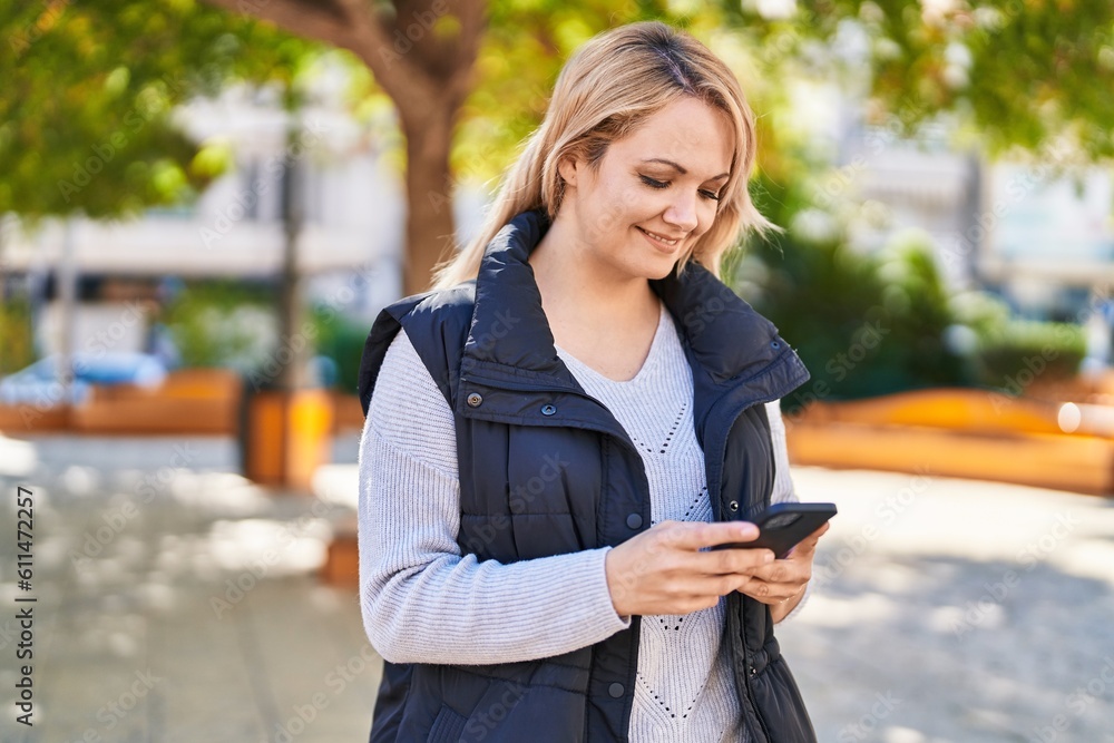 Fototapeta premium Young blonde woman smiling confident using smartphone at park
