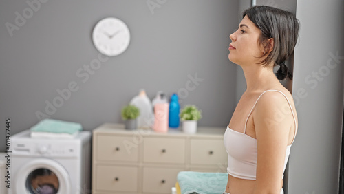 Young beautiful hispanic woman stressed leaning on wall at laundry room