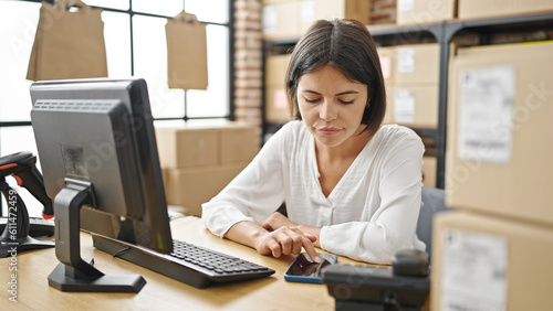 Young beautiful hispanic woman ecommerce business worker using smartphone while work at office
