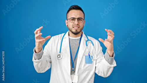 Hispanic man doctor angry and stressed over isolated blue background © Krakenimages.com