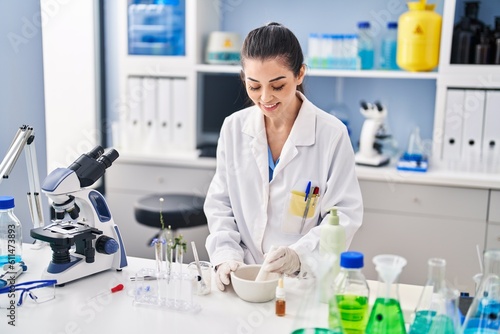 Young beautiful hispanic woman scientist smiling confident mixing sample at laboratory