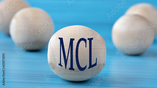 The letters MCL are depicted on a wooden round ball on a blue background photo