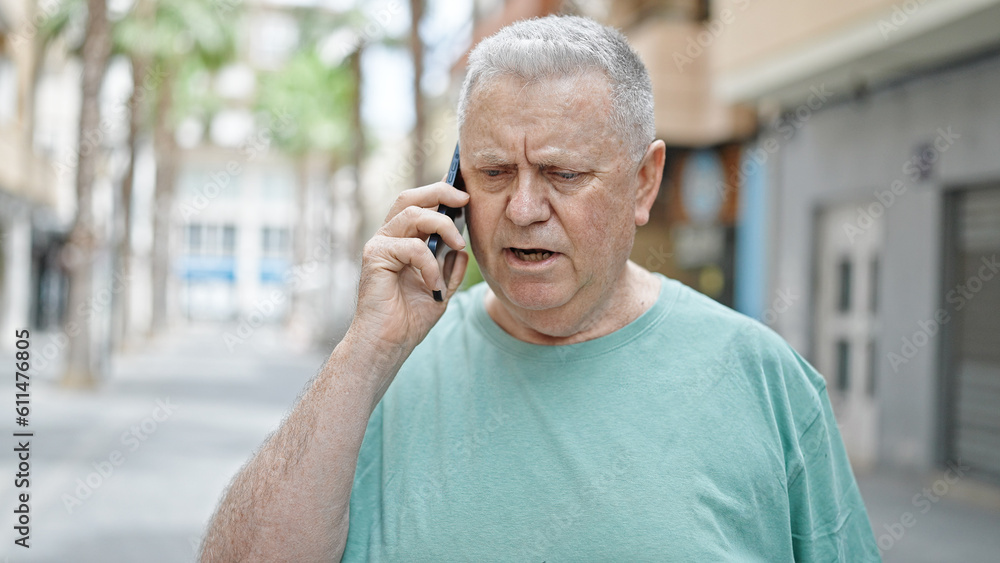 Middle age grey-haired man talking on smartphone with serious expression at street Middle age grey-haired man talking on smartphone with serious expression at street