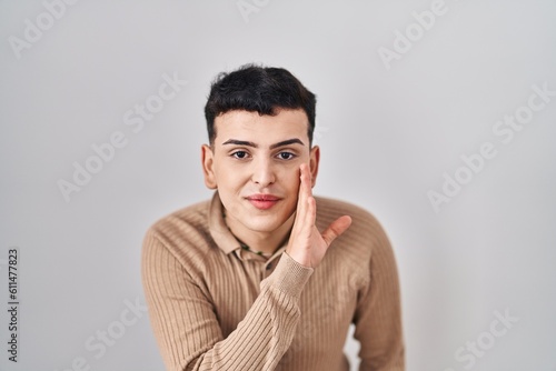 Non binary person standing over isolated background hand on mouth telling secret rumor, whispering malicious talk conversation