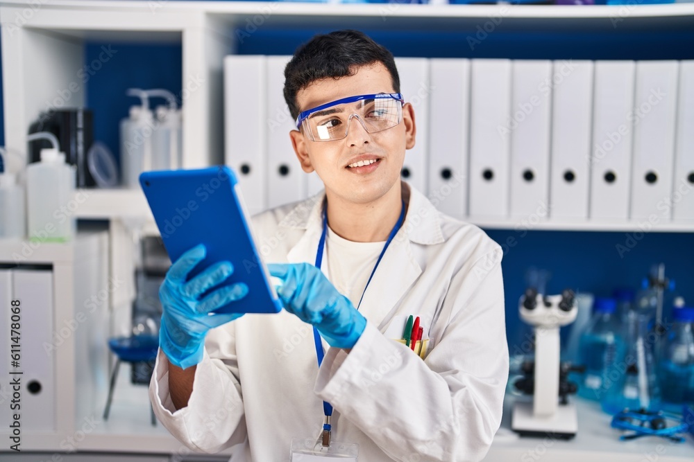 Young non binary man scientist smiling confident using touchpad at laboratory Young non binary man scientist smiling confident using touchpad at laboratory