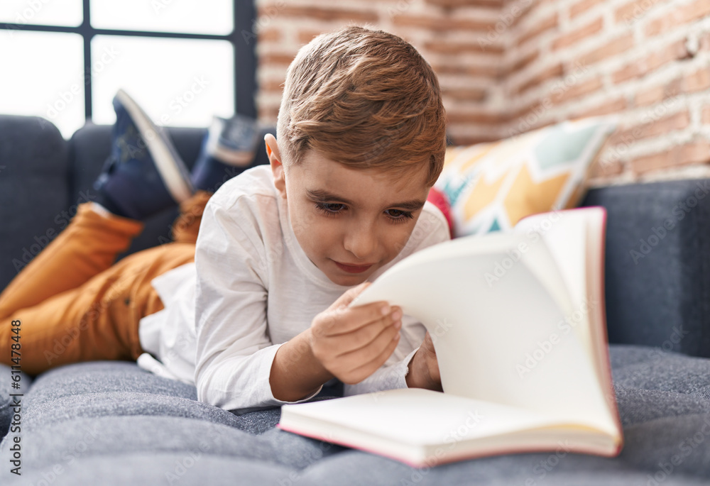 Adorable hispanic boy reading book lying on sofa at home Adorable hispanic boy reading book lying on sofa at home