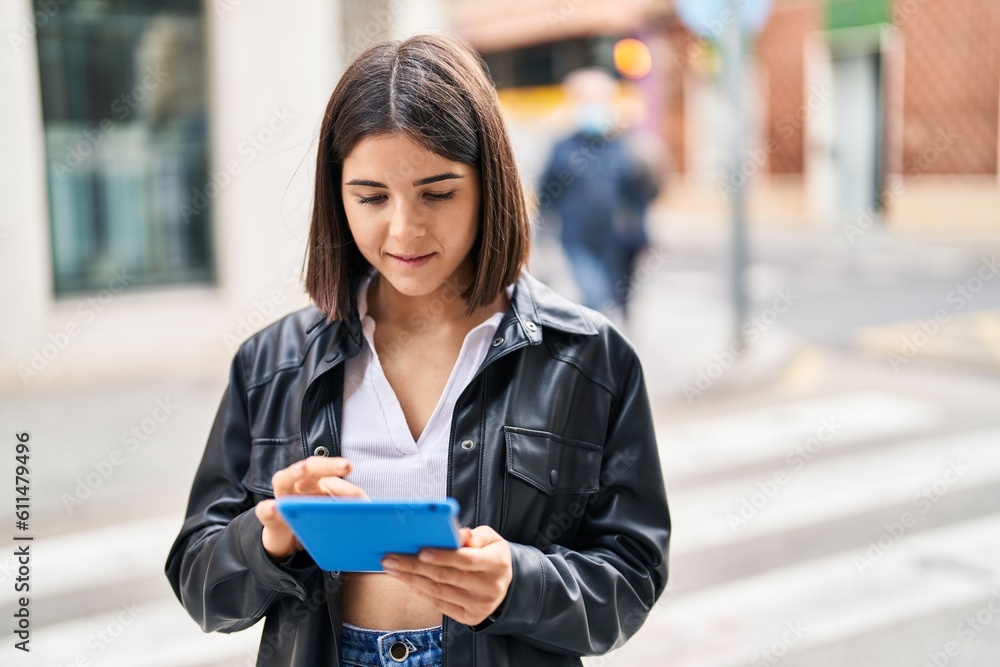 Young beautiful hispanic woman smiling confident using touchpad at street