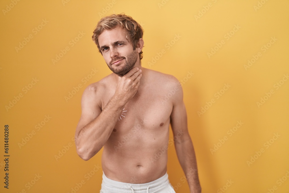Caucasian man standing shirtless wearing sun screen touching painful neck, sore throat for flu, clod and infection