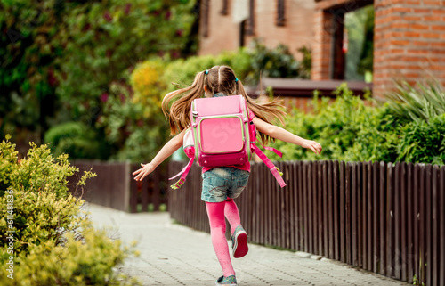 little girl with a backpack run to school. back view © tan4ikk