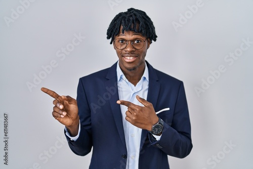 Young african man with dreadlocks wearing business jacket over white background pointing aside worried and nervous with both hands, concerned and surprised expression