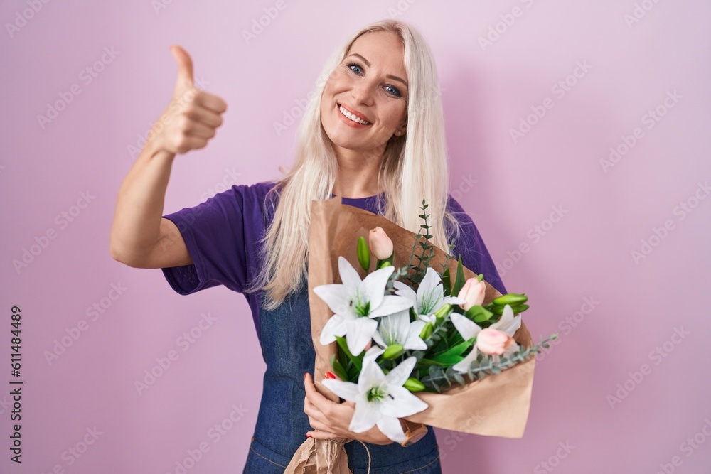 Caucasian woman holding bouquet of white flowers approving doing positive gesture with hand, thumbs up smiling and happy for success. winner gesture.