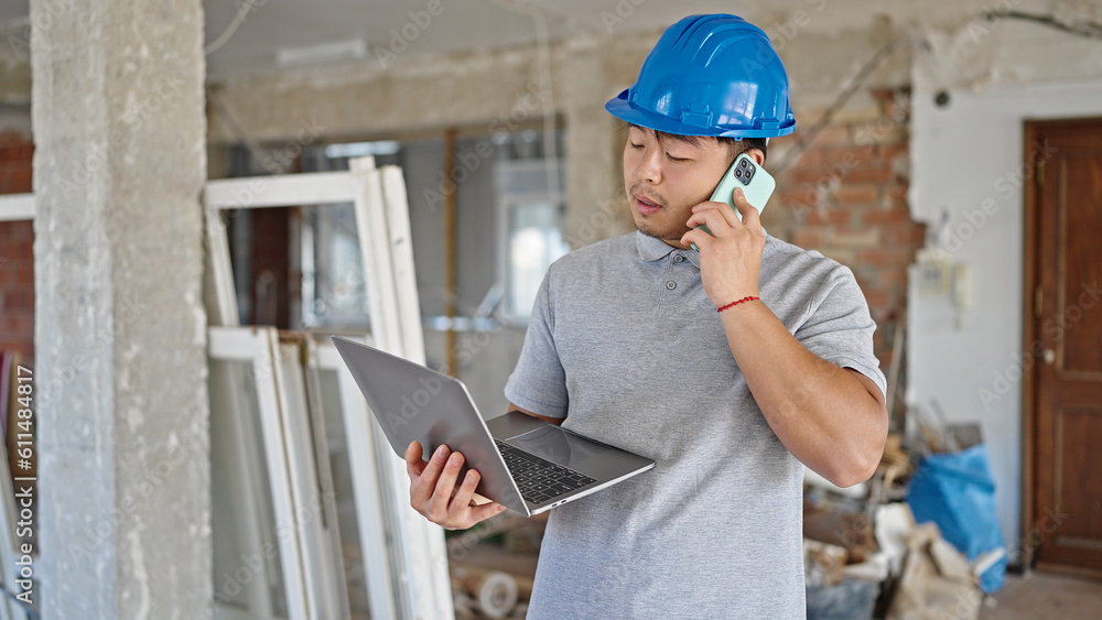 architect using laptop talking on smartphone at construction site architect using laptop talking on smartphone at construction site