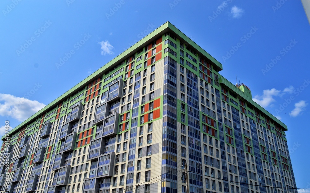 A large multi-storey green orange residential building against a blue sky in good weather