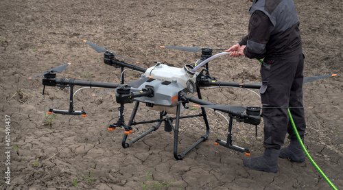 The drone operator fills the tank of the sprayer with fertilizer