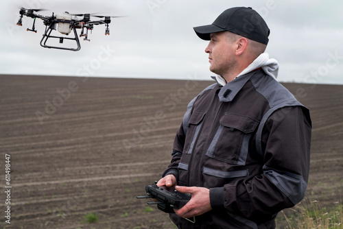 Male farmer hold the remote control of an agricultural sprayer drone