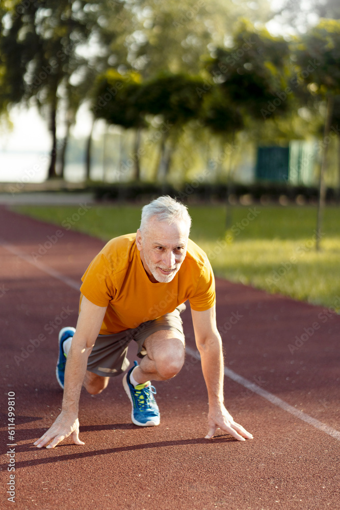 Vertical view of the purposeful senior athletic runner standing at the starting position