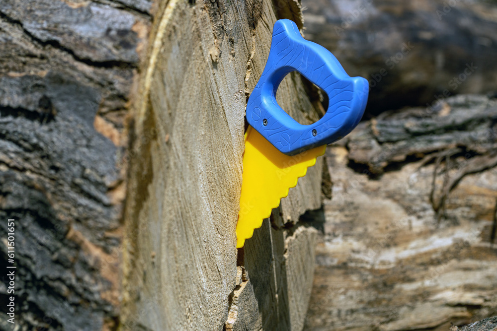 blue and yellow hand saw sawing a large tree blue and yellow hand saw sawing a large tree