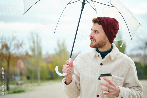 Man with a coffee and transparent umbrella in winter. © Ladanifer