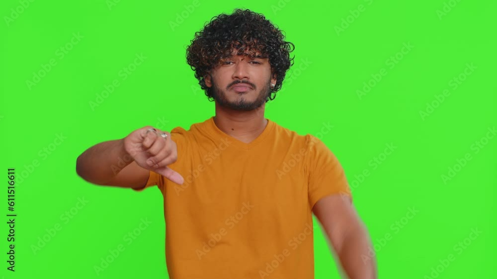 Dislike. Upset unhappy indian man in shirt showing thumbs down sign gesture, expressing discontent, disapproval, dissatisfied, dislike. Handsome young guy. Indoors studio shot on chroma key background Dislike. Upset unhappy indian man in shirt showing thumbs down sign gesture, expressing discontent, disapproval, dissatisfied, dislike. Handsome young guy. Indoors studio shot on chroma key background