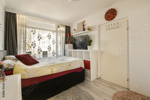 a bedroom with a bed, desk and television on the wall in front of the bed is decorated with flowers