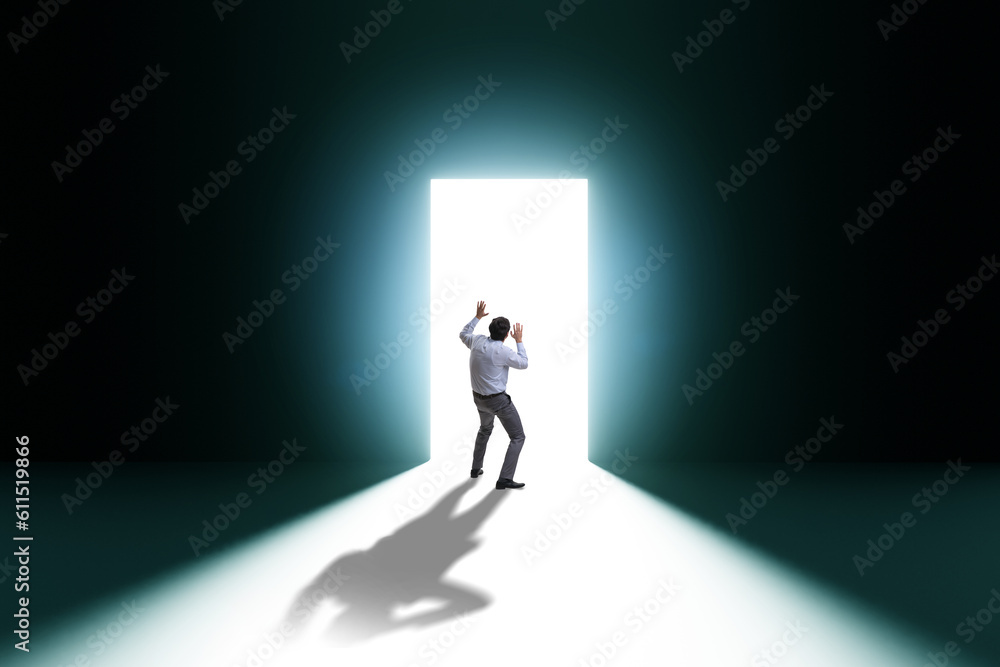 Businessman entering backlit door in escape concept Businessman entering backlit door in escape concept