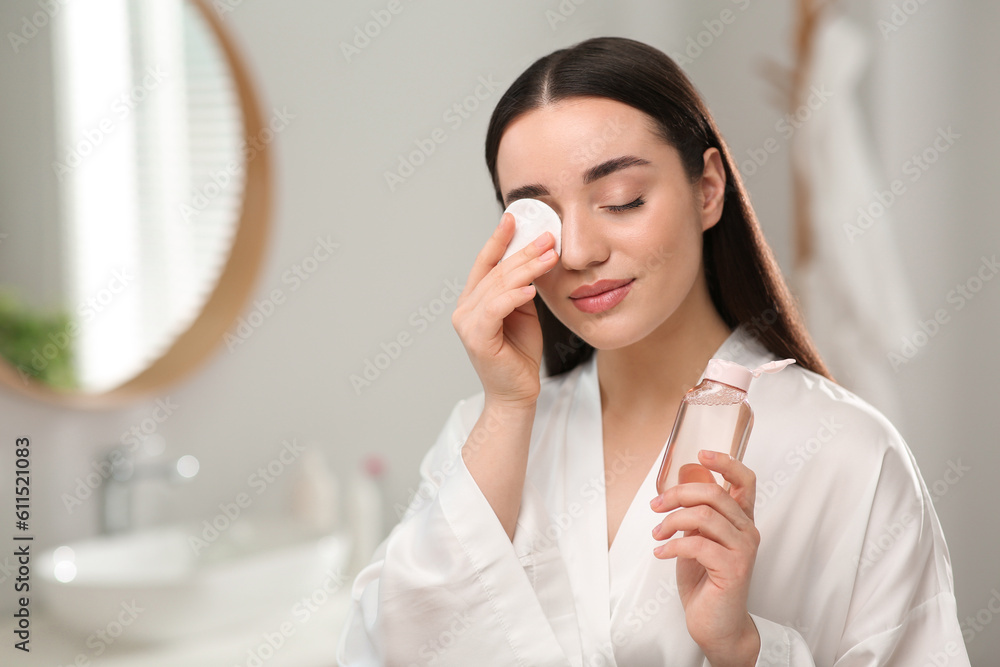 Beautiful woman removing makeup with cotton pad indoors Beautiful woman removing makeup with cotton pad indoors