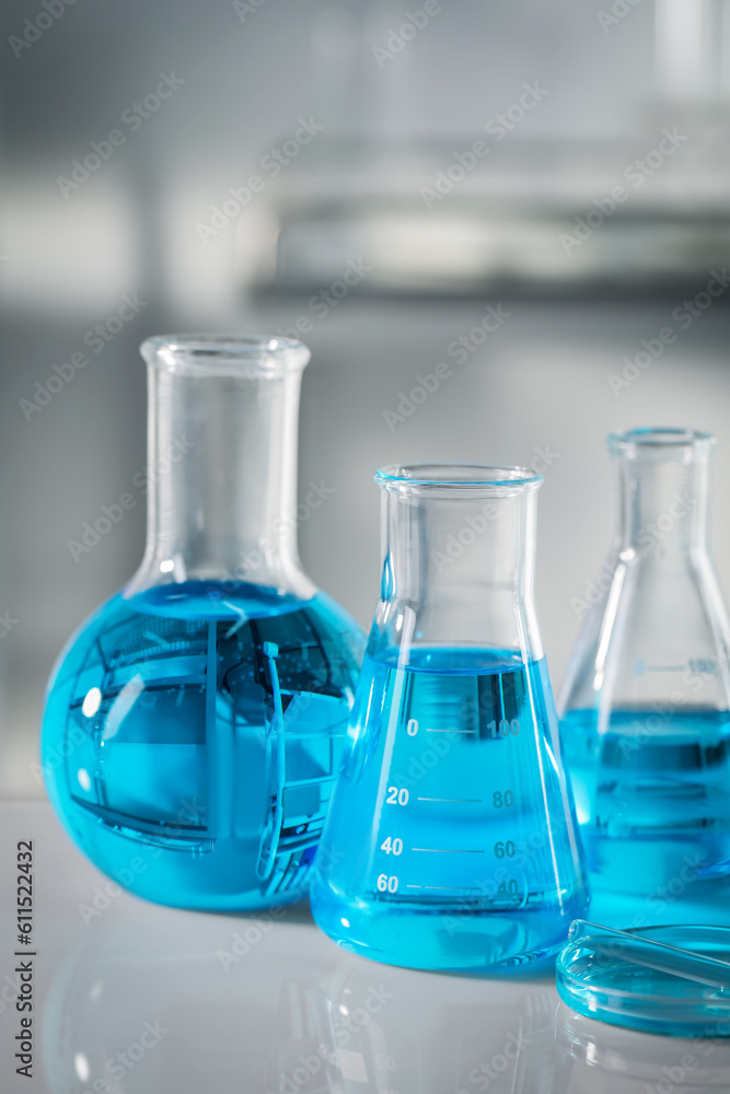 Different glassware with light blue liquid on table in laboratory Different glassware with light blue liquid on table in laboratory