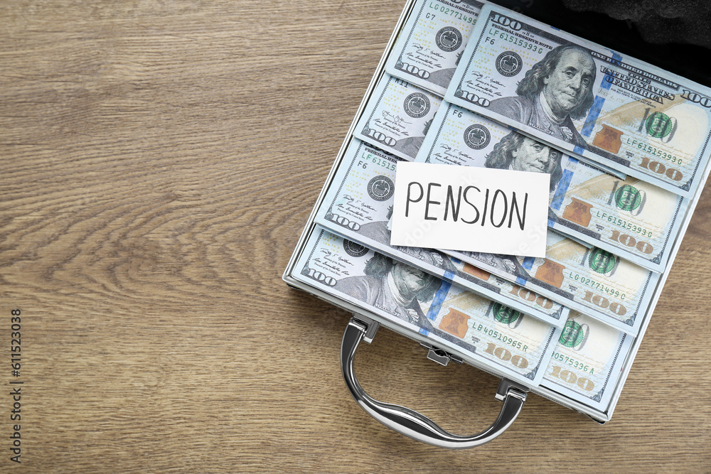 Card with word Pension and case of dollar banknotes on wooden table, top view. Space for text Card with word Pension and case of dollar banknotes on wooden table, top view. Space for text