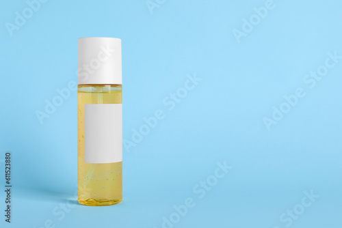 Bottle with cosmetic oil on light blue background, space for text