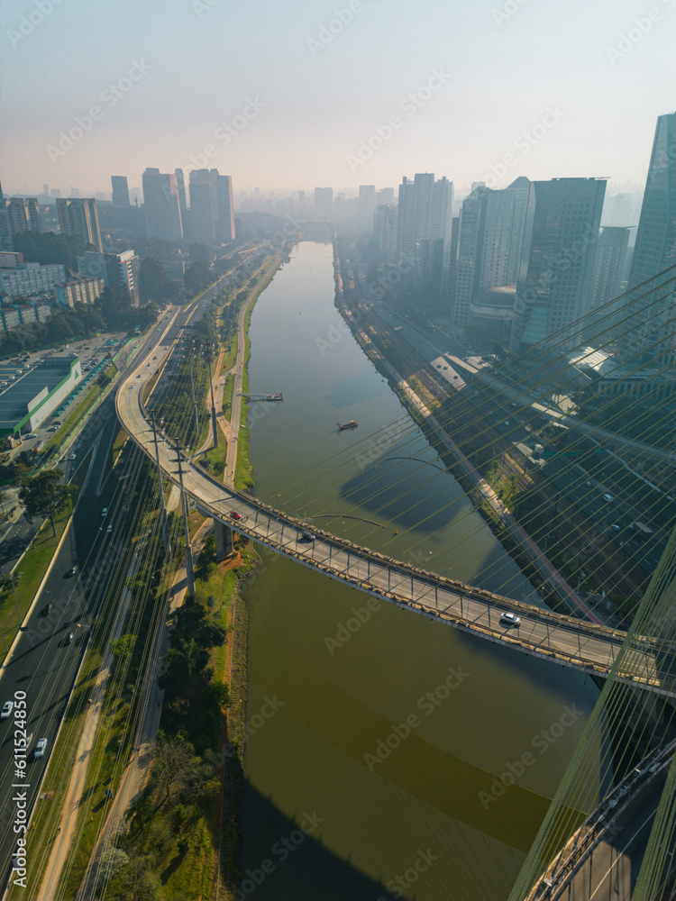 Obraz premium 2023 view of the Pinheiros river with modern buildings beside it and the famous Octavio Frias de Oliveira bridge in the city of São Paulo.