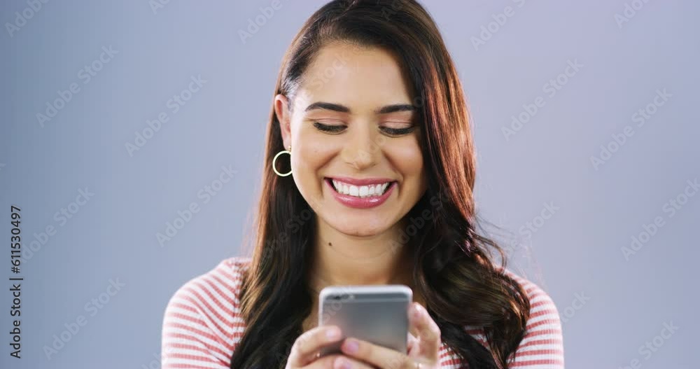 Mobile cellphone, face and happy woman typing, texting or reading gossip blog, online app and scroll on website. Portrait, happiness and studio person check social media isolated on grey background Mobile cellphone, face and happy woman typing, texting or reading gossip blog, online app and scroll on website. Portrait, happiness and studio person check social media isolated on grey background