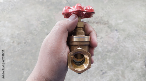 Quadro su tela The hand hold a brass stop valve by front view ,valve turning to open or close the water flow