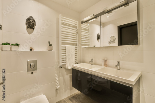 a modern bathroom with white tiles and black countertops  along with a tv mounted on the wall above the sink