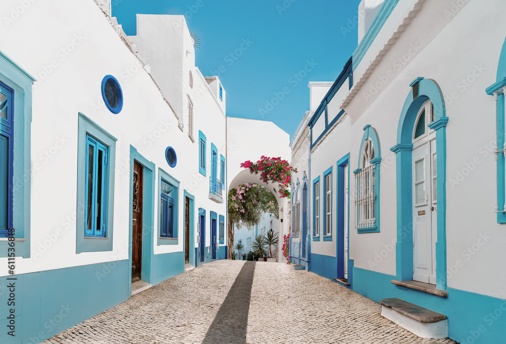 Street in fishermen village with white and blue houses and typical Portuguese pavement in Olhao, Algarve region - Popular travel destinations in Portugal