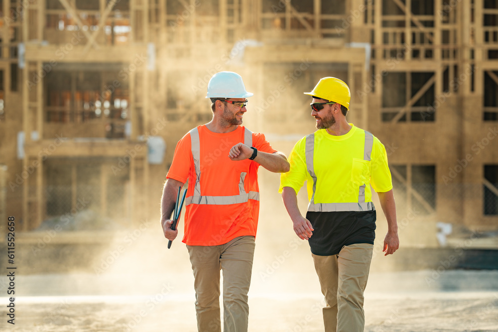 Two builders in a hard hat is busy working on a construction project at a site. A builders workes in a helmet near building construction sites. Two builders in a hard hat is busy working on a construction project at a site. A builders workes in a helmet near building construction sites.