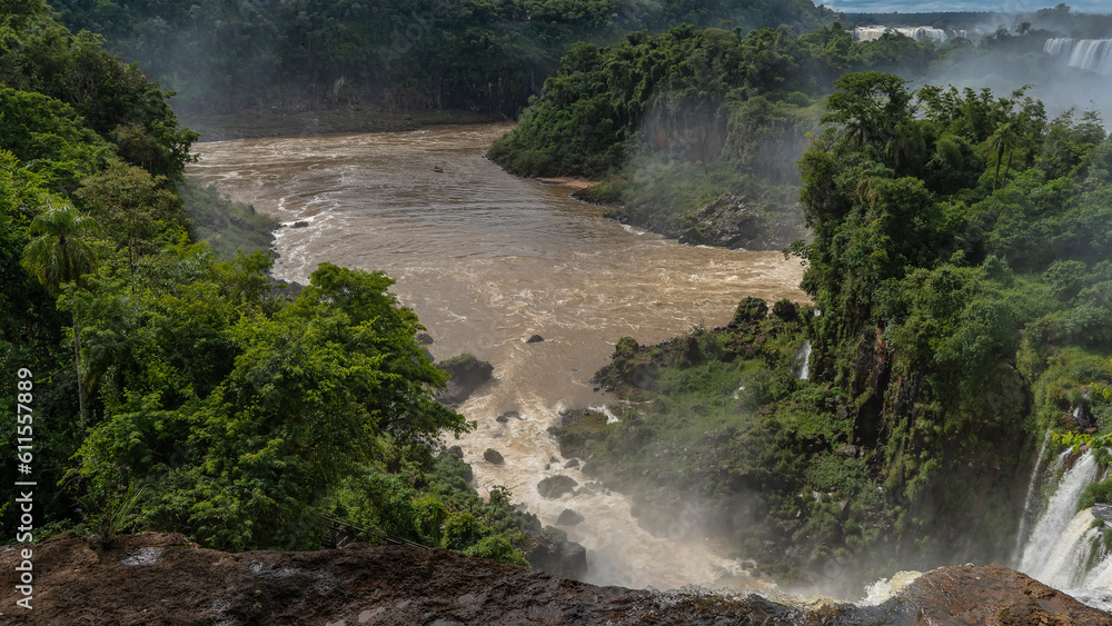 Iguazu Falls. Water flows down from the ledge into the riverbed. Spray and fog. Lush tropical vegetation all around. Argentina. Iguazu Falls. Water flows down from the ledge into the riverbed. Spray and fog. Lush tropical vegetation all around. Argentina.