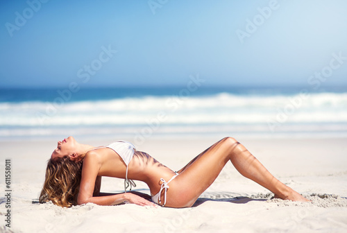Woman on beach sand  model in bikini and body in sexy pose  nature and travel with summer fashion on vacation. Female person relax  sun and sea with sunbathing outdoor and holiday in stylish swimsuit
