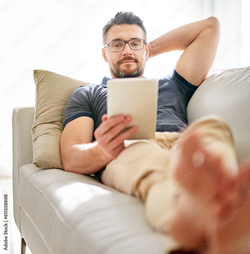 Tablet, sofa and man relaxing at his home reading a ebook or online blog on the internet. Rest, browsing and mature male person watching a video on social media with digital technology in living room Tablet, sofa and man relaxing at his home reading a ebook or online blog on the internet. Rest, browsing and mature male person watching a video on social media with digital technology in living room