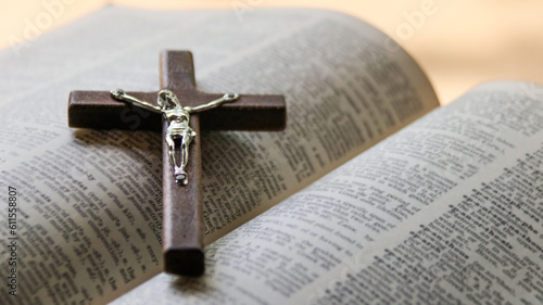 Close up dark brown wooden cross on old books with blur background                                                            