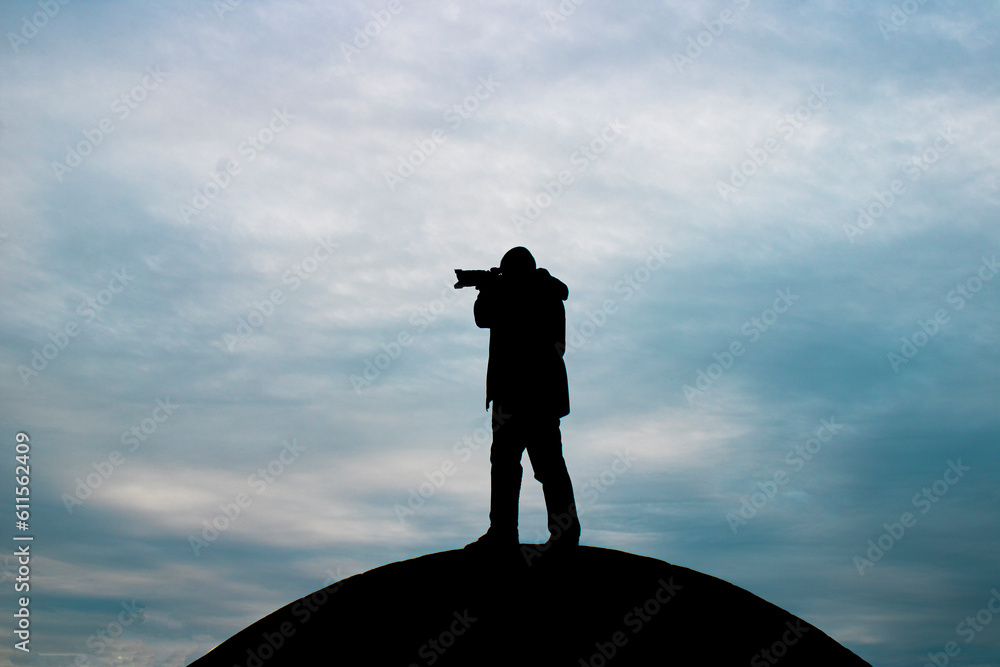 Photographer silhouette. Person holding camera and focusing on a point.