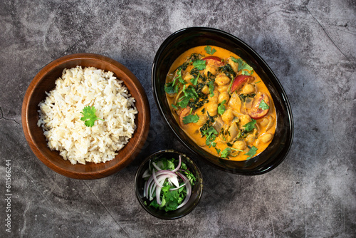 Chickpea curry with spinach has brown rice on black stale table healthy vegan food concept.